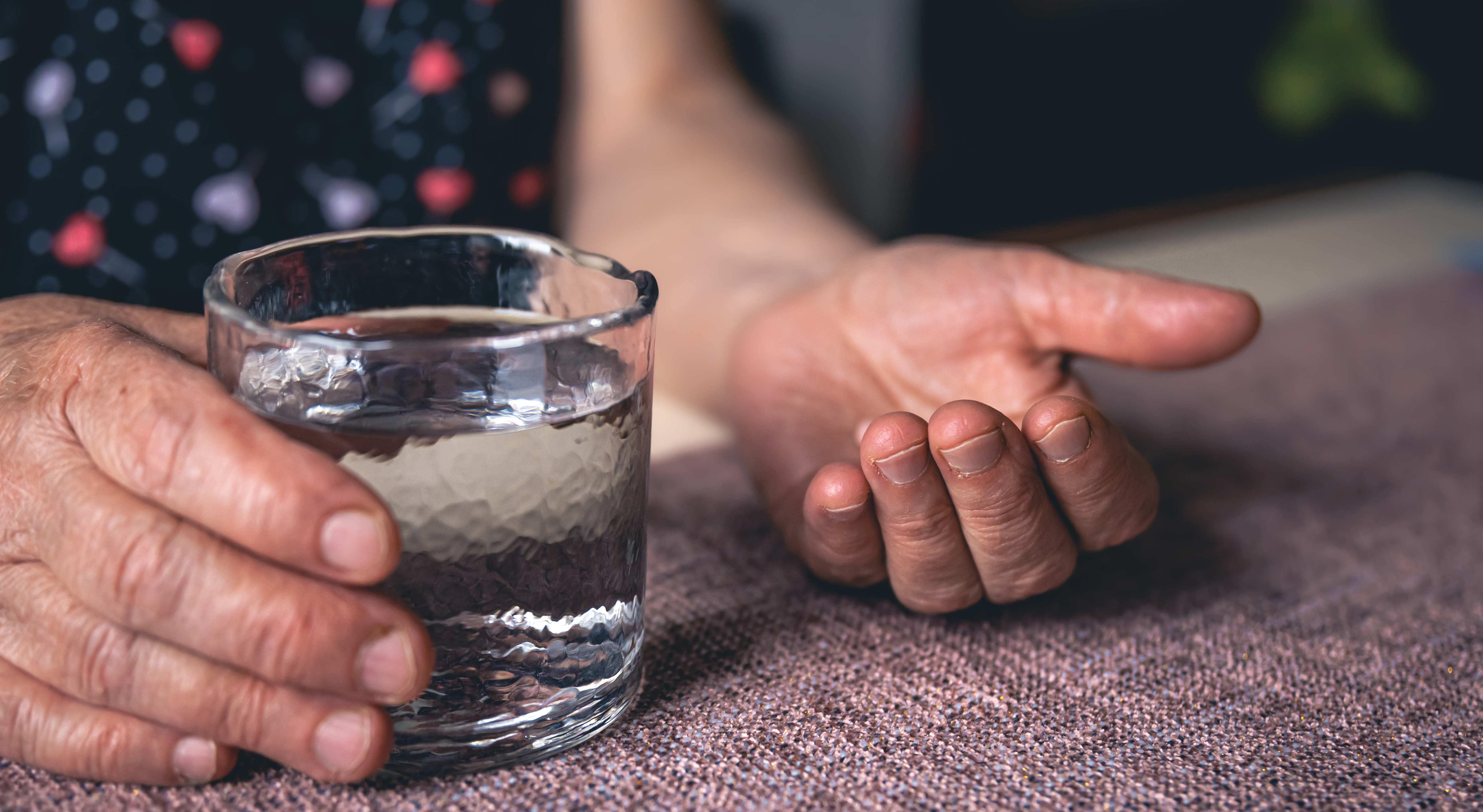 Mains âgées tenant un verre